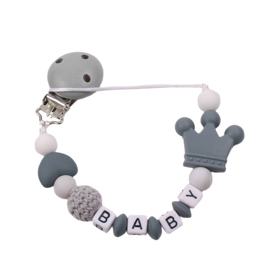 Silicone pacifier chain with crown and 'BABY' letter beads on a white background